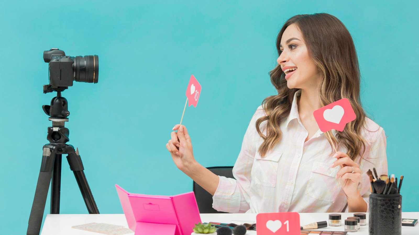 Explosão do Marketing de Influenciadores: Tendências para 2025 com criadora de conteúdo sorrindo enquanto grava vídeo para redes sociais segurando ícones de curtidas em um estúdio colorido.